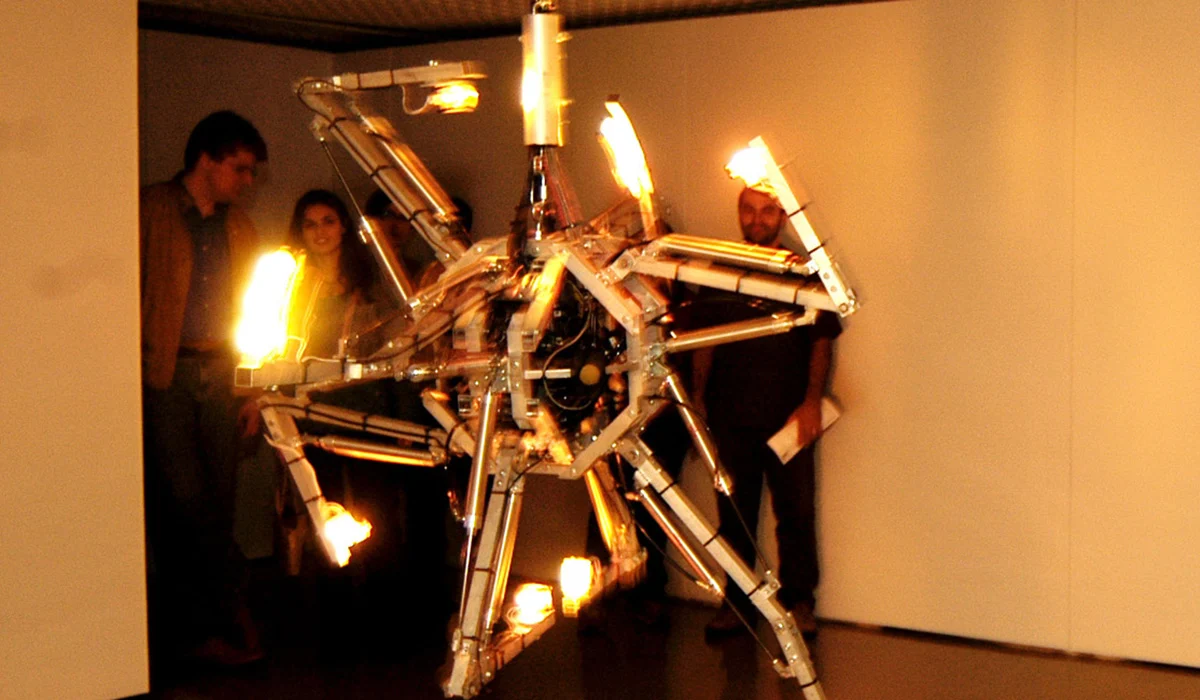Photo de spectateur regardant l'œuvre Prehysterical Machine, par Bill Vorn. Installation robotique suspendue. Réalisée en 2002 et présentée lors de la 9e Festival international de Vidéo/Art/Électronique, Lima, en 2005.