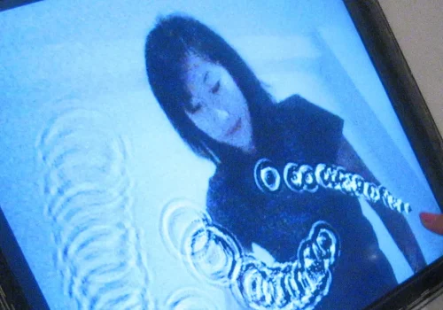 Personne interagissant avec une tablette numérique, sur laquelle se trouve l'image d'une femme. Œuvre Digitale par Alexandre Castonguay. Réalisée entre 2003-2004.