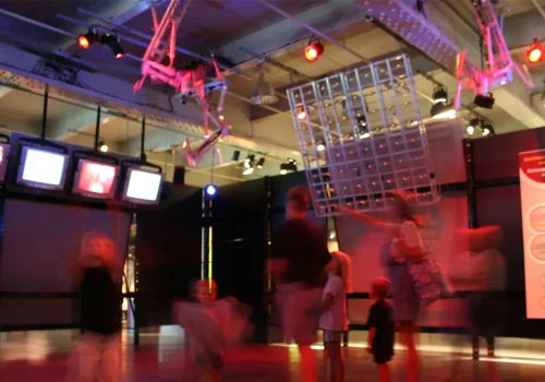 Photo d'un espace d'exposition avec des spectateurs regardant l'installation robotique suspendue Rotoscopic Machines, par Bill Vorn. Réalisée en 2005. Présentée au Centre des sciences de Montréal.