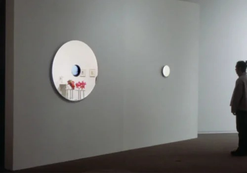 Personne qui regarde un miroir à côté de l'œuvre Tact, par Jean Dubois. Installation interactive, 2000-2001.